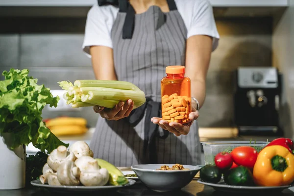 Mutfakta kadın ellerinin kereviz ve besin takviyeleri ya da vitaminler tutmasını engelleyin. Seçim, dengeli diyet ve sağlık konsepti