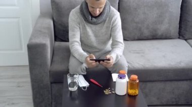 Evdeki hastalık sırasında akıllı telefondan bilgisayar oyunu oynayan genç adam.