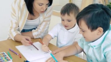 Annem iki oğlana albümde işaret çizmeleri için yardım ediyor. Okul öncesi eğitim