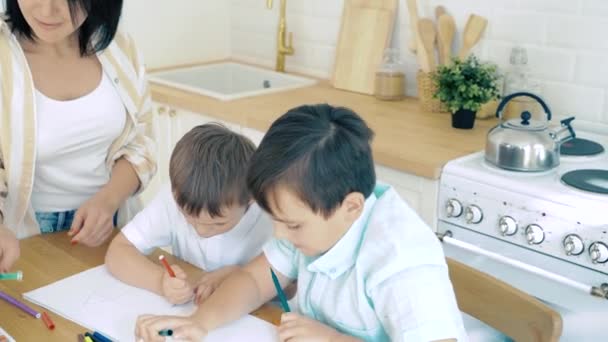 2人の子供と母親が台所で紙の上にフェルトペンで描く — ストック動画