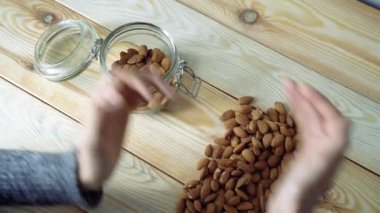 Kadın elleri cam kavanozdaki bademleri değiştiriyor. Üst görünüm