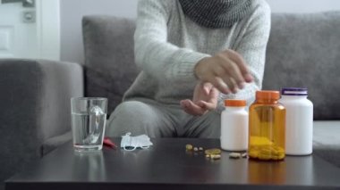 İlaçlar, kapsüller ve termometre masanın üzerinde. İlaç alan adam..