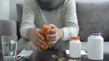 İlaçlar, kapsüller ve termometre masanın üzerinde. İlaç alan adam..