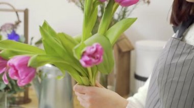 Çiçekçi, çiçekçi, çiçekçi ya da atölyede lale buketi süsleyen kadın elleri.