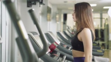 Vücut geliştiren kadın spor salonunda koşu bandında yürüyor. Spor salonunda koşu makinesi kullanan atletik bir kız..