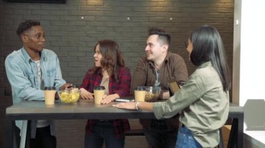 Bir grup arkadaş ya da iş arkadaşı evde ya da ofiste beşlik çakan genç bir adama gülümsüyor..