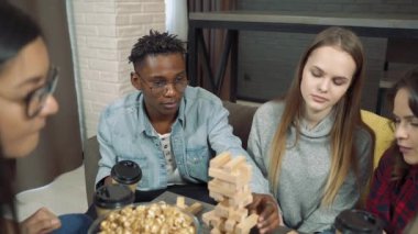 Evde blok kaldırma oyunu oynayan bir grup mutlu arkadaş.