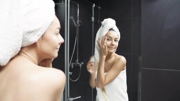 Jovem Feliz Com Toalha Cabeça Tocando Rosto Depois Aplicar Creme — Vídeo de Stock