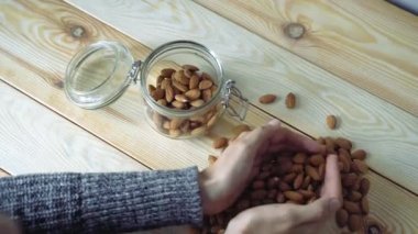 Kadın elleri, badem fıstıklarını kabın içine koyuyor.