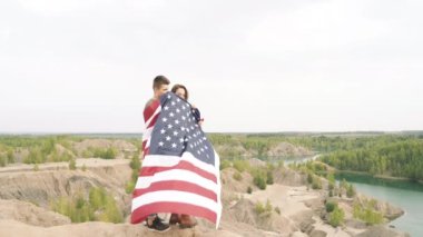 Amerikan bayrağına sarılmış mutlu çift. Bağımsızlık Günü, yaşam tarzı, seyahat kavramı.