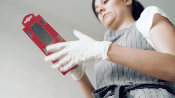 穿着围裙和手套的年轻妇女在工作前从箱子里拖着铲子 — 图库视频影像