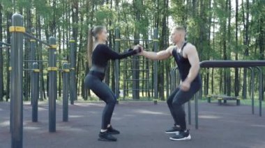 Sportif çift dışarıda birlikte çömeliyor.