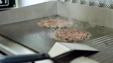 Hamburger için biftek ve domuz pirzolası. Şef tavadan kızarmış köfte topluyor.