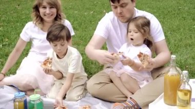 Mutlu aile pizza yiyor ve piknikte eğleniyor.