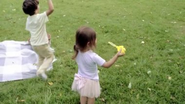 Tatlı çocuklar kabarcıklar çıkarıyor ve dışarıda birlikte oynuyorlar..