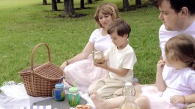 Piknik sırasında çimlerin üzerinde dinlenen çocukları olan mutlu bir aile. Aile hayatında mutluluk ve uyum.