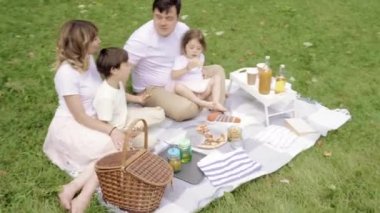 Mutlu aile pizza yiyor ve piknikte eğleniyor.