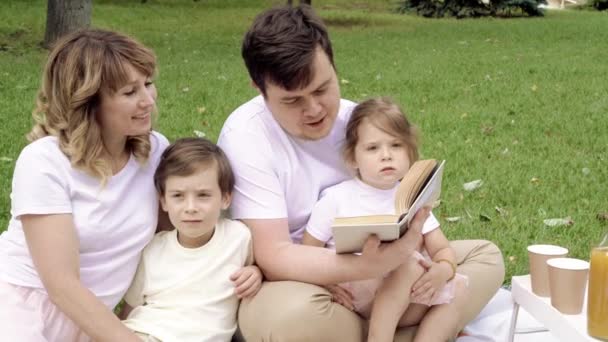 Familia Feliz Con Niños Leyendo Libro Sobre Picnic Aire Libre — Vídeo de stock