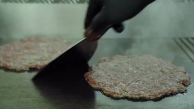 Hamburger için biftek ve domuz köftesi. Şef tavadaki etin hazır olup olmadığını kontrol ediyor..