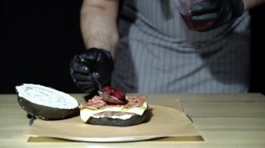 Şefin elleri nefis bir siyah burger pişiriyor. Füme domuz pastırması ve kirazlı..