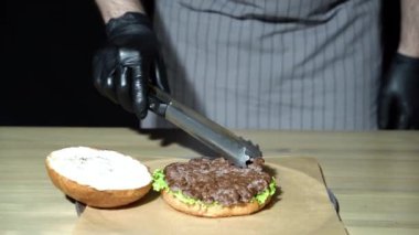 Şef hamburgeri hazırlıyor. Hamburger için et döşeyen adamın ellerini kapat..