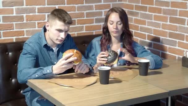 Ευτυχισμένο Ζευγάρι Τρώει Χάμπουργκερ Ένα Καφέ Σπίτι — Αρχείο Βίντεο