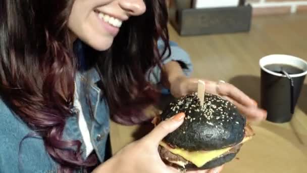 Junges Mädchen Hält Saftigen Schwarzen Burger Café Oder Hause — Stockvideo