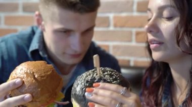 Sevgi dolu bir çift kafede konuşuyor ve hamburger yiyor.