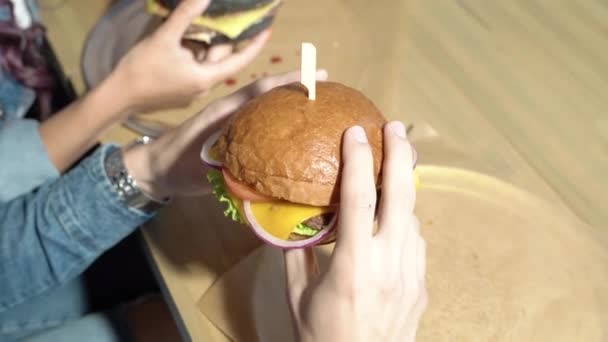 Close Van Twee Heerlijke Hamburgers Handen Van Een Jong Stel — Stockvideo