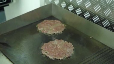 Hamburger köftesi pişiriyorum. Aşçı tavada et çeviriyor..