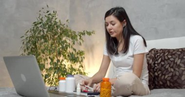 İnternette doktorla konuşan bir kadın hasta dizüstü bilgisayarla tavsiye mektuplarını bir deftere yazıyor. Teletıp ve internet danışma kavramı.