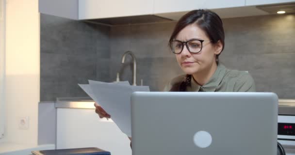 ノートパソコンで仕事をしている眼鏡の若い女性に焦点を当て 自宅で文書でレポートを作成します — ストック動画