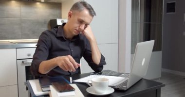 İşadamı belgeleri okuyor ve evde dizüstü bilgisayarla çalışıyor.