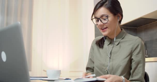 Egy Üzletasszony Videokommunikáción Beszél Fejhallgatóval Laptoppal Jegyzetel Egy Jegyzetfüzetben Online — Stock videók