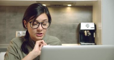 İş kadını kulaklık ve dizüstü bilgisayar kullanarak video iletişimi kuruyor ve not defterine not alıyor. Çevrimiçi eğitim ya da mesafe çalışması.