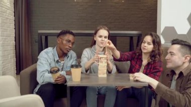 Bir grup çok ırklı mutlu arkadaş blok kaldırma oyunu oynuyor ve evde birlikte eğleniyorlar..