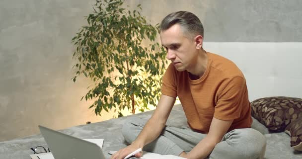 Genç Adam Dizüstü Bilgisayarda Çalışıyor Evdeki Defterine Alıyor Çevrimiçi Eğitim — Stok video