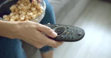 Evdeki uzaktan kumandayla TV 'nin kanallarını değiştiren kadın ellerini kapat..