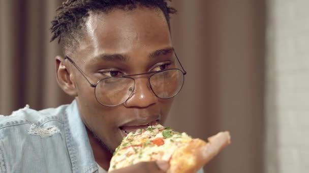 Portret Van Een Afrikaanse Jongeman Die Een Stuk Pizza Eet — Stockvideo