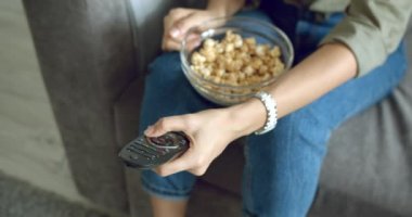 Evdeki uzaktan kumandayla TV 'nin kanallarını değiştiren kadın ellerini kapat..