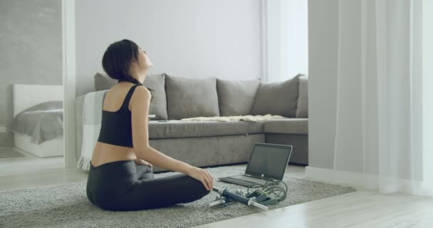 スポーティ若い女性は自宅でノートパソコンを使用してオンライン演習ストレッチを行う 健康的なライフスタイルのコンセプト 自己分離中のスポーツ — ストック動画