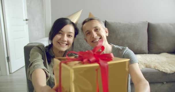 头戴生日礼帽的快乐夫妻在家中为他们的订户或朋友们保存礼物和录像 社交网络和在线交流 — 图库视频影像