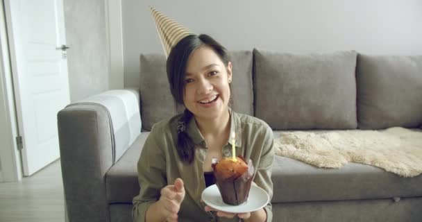 オンラインコミュニケーションを楽しむ幸せな若い女性の肖像画や誕生日を祝うビデオを記録し 自宅でケーキの上にろうそくを吹き消す — ストック動画