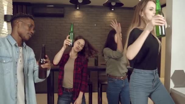 多人種の若者たちがリビングルームのホームパーティーで楽しんでビールを飲んで踊っています 若者と休日の概念 — ストック動画
