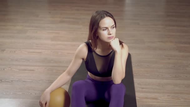 在工作室或家里的地板上锻炼后 年轻女人拿着健身球休息 — 图库视频影像