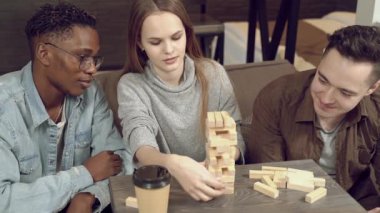 Bir grup çok ırklı mutlu arkadaş blok kaldırma oyunu oynuyor ve evde birlikte eğleniyorlar..