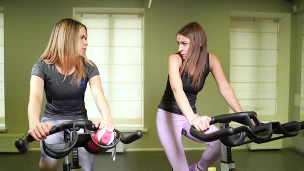 Two Young Attractive Women Cycling Machines Doing Cardio Training Together — Stock Video