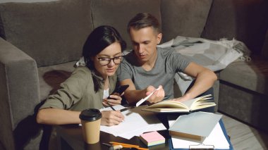 Genç çift, yeni bir apartman dairesinin ortak projesini ya da tasarımını tartışıyor. Evde yerde oturuyor.