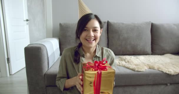 戴着生日礼帽的快乐的年轻女人带着礼物 记录着一段视频 或者在网上和他的朋友聊天 社交网络和在线交流 — 图库视频影像