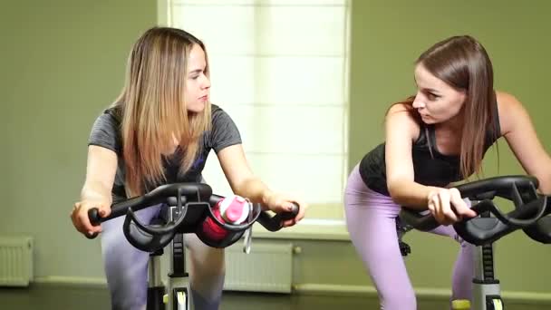 Twee Jonge Vrouwen Fiets Machines Doen Cardiotraining Samen Sportschool — Stockvideo